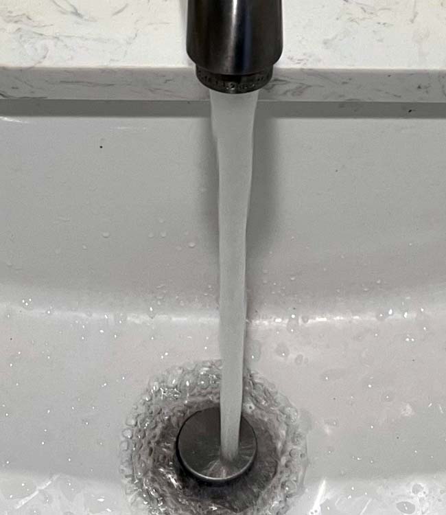 Water Running Out of a Bathroom Faucet Into a Sink