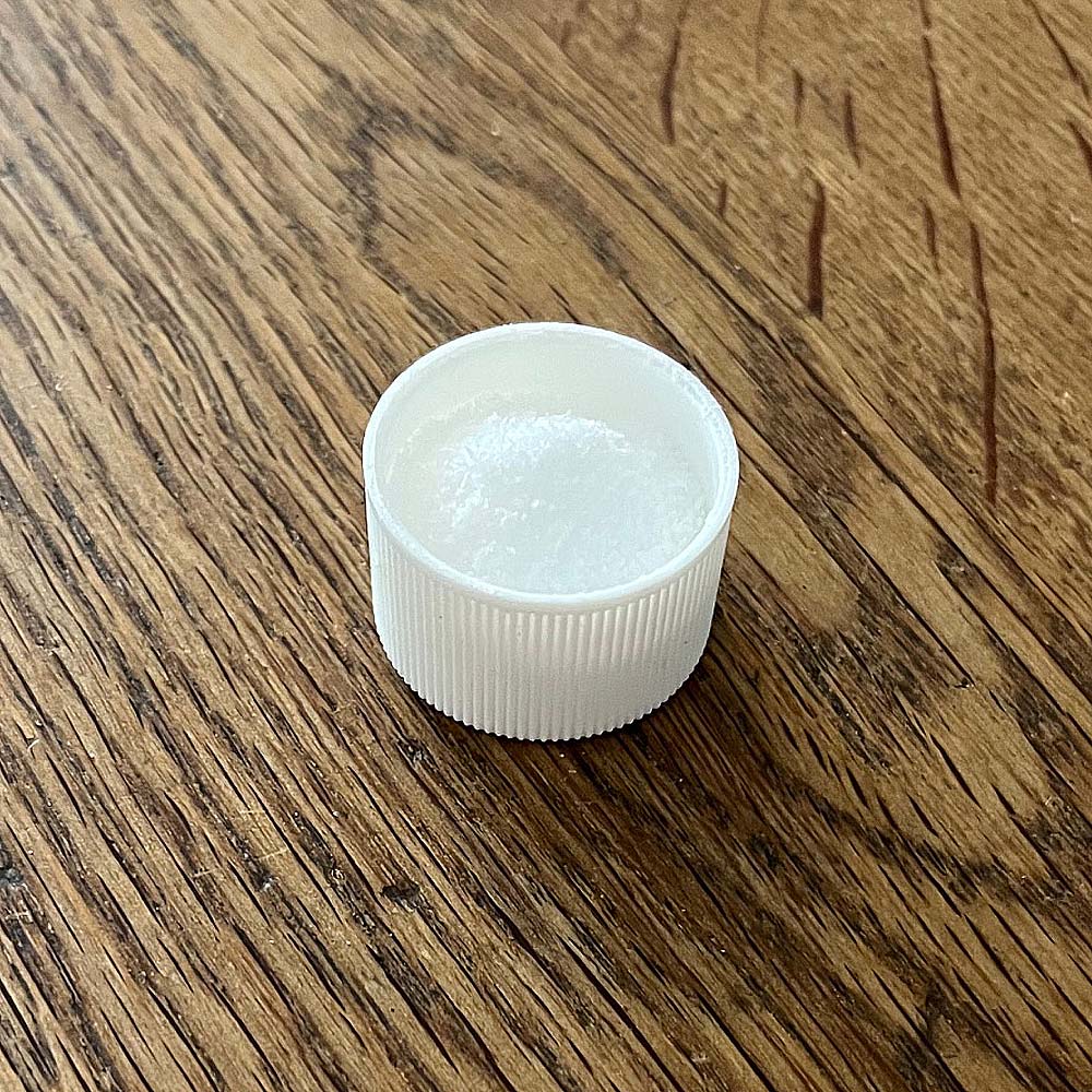 Serving Size Cap Filled With Unscented Solution Salt on a Wood Table