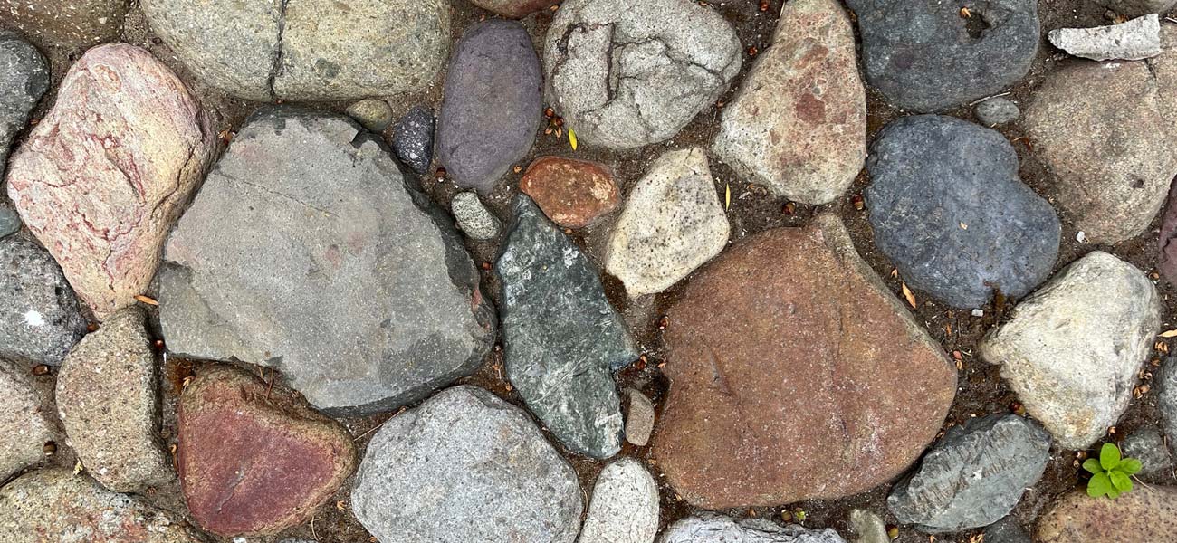 Various Brown, Grey and Blue River Rocks and Stones Embedded in the Ground